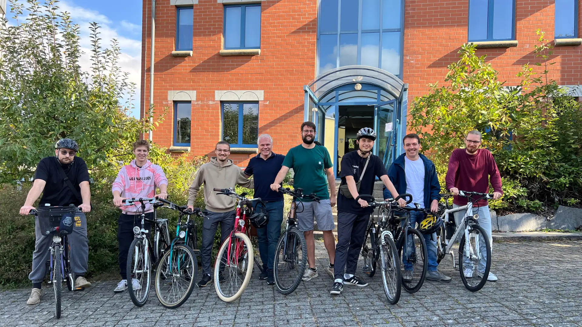 Gruppenfoto eines gut gelaunten Teams mit Fahrrädern vor dem Bürogebäude vor dem Start der Radtour am Bodensee